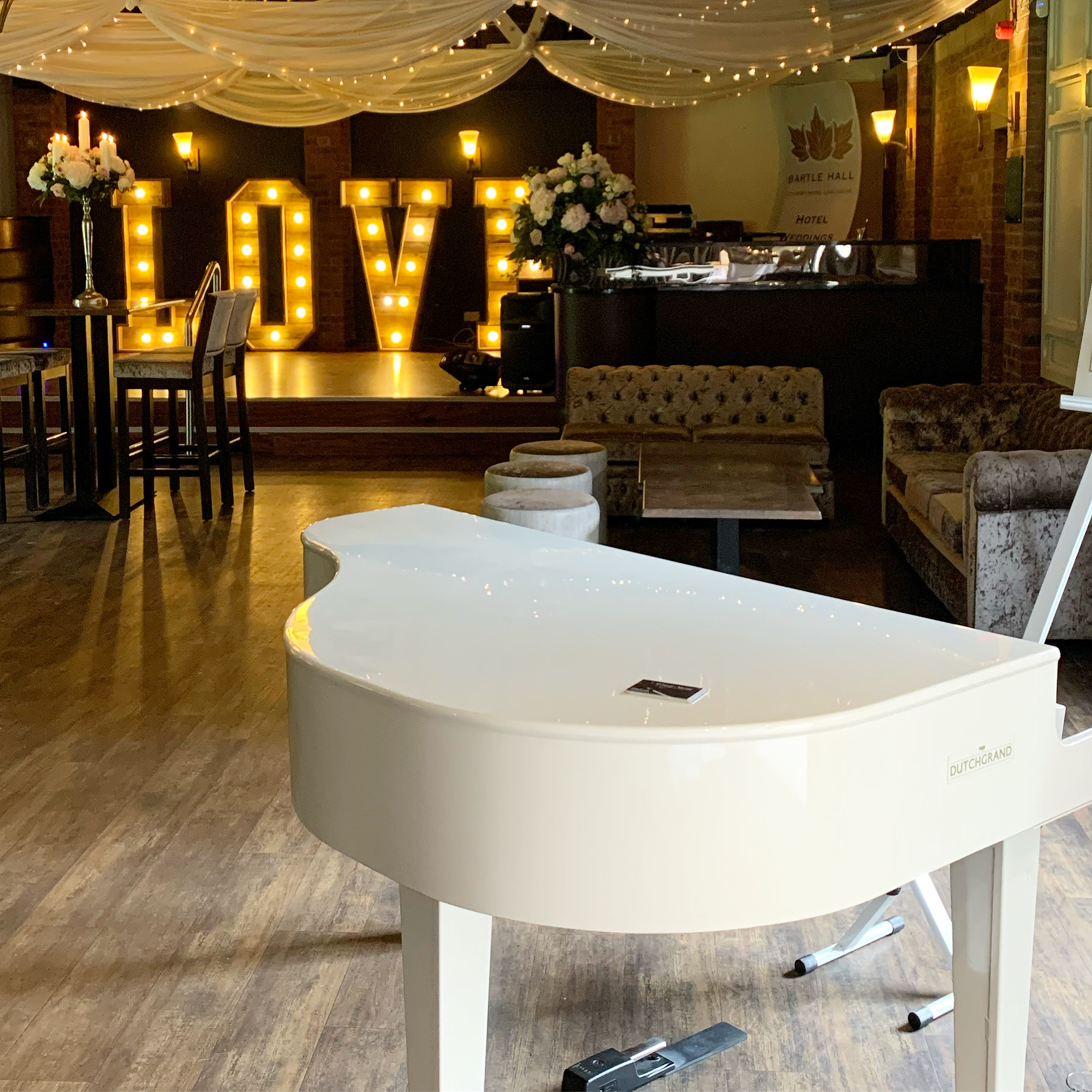 Bartle Hall wedding pianist Craig Smith's white baby grand piano set up ready to welcome guests to the reception in the Coaching Barn