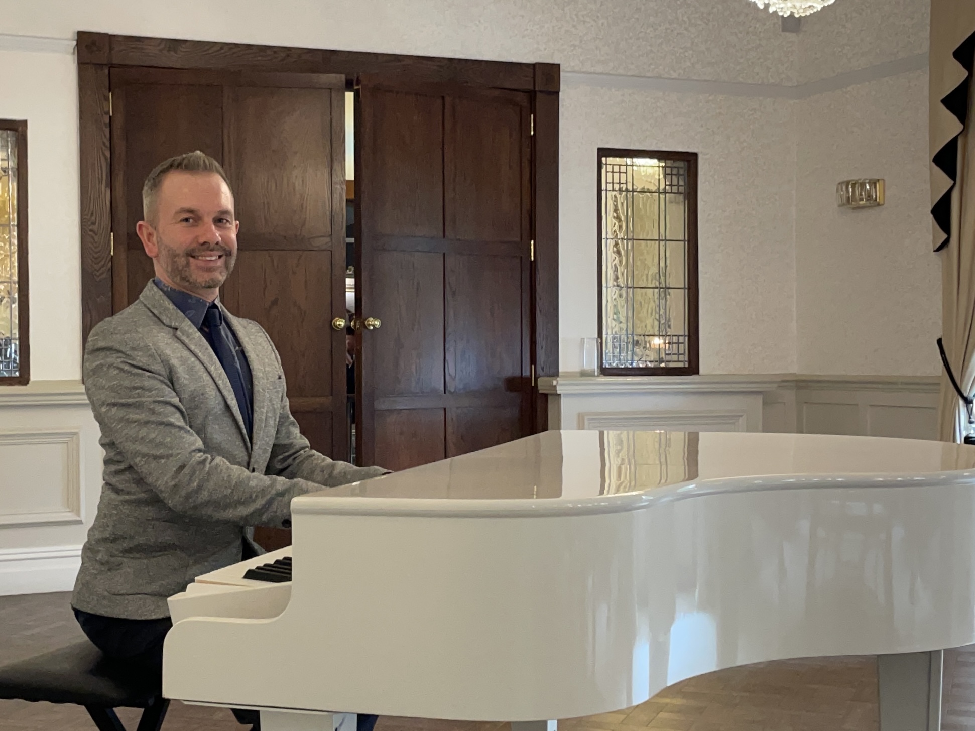 Bartle Hall wedding pianist Craig Smith smiles from his white piano before a wedding ceremony