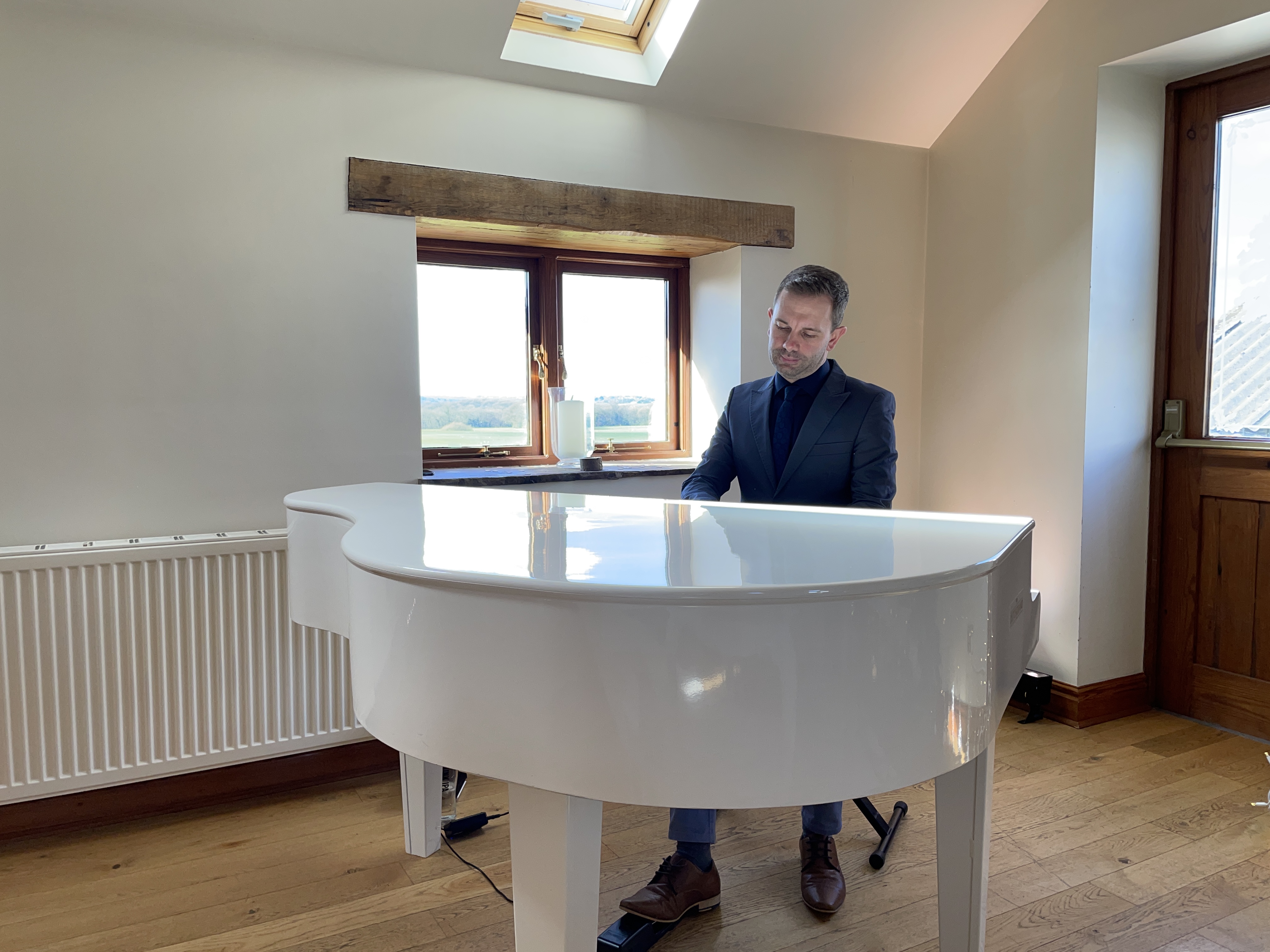 Wedding pianist Craig Smith playing his white piano during a Beeston Manor wedding ceremony