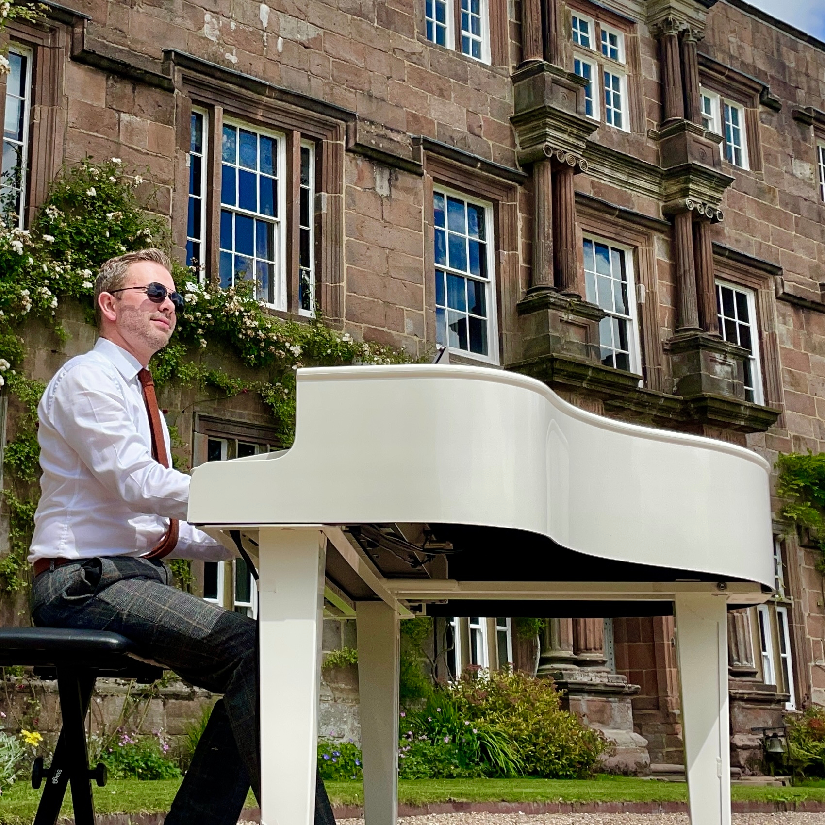 Wedding pianist Craig Smith plays in the Browsholme Hall gardens for a wedding ceremony