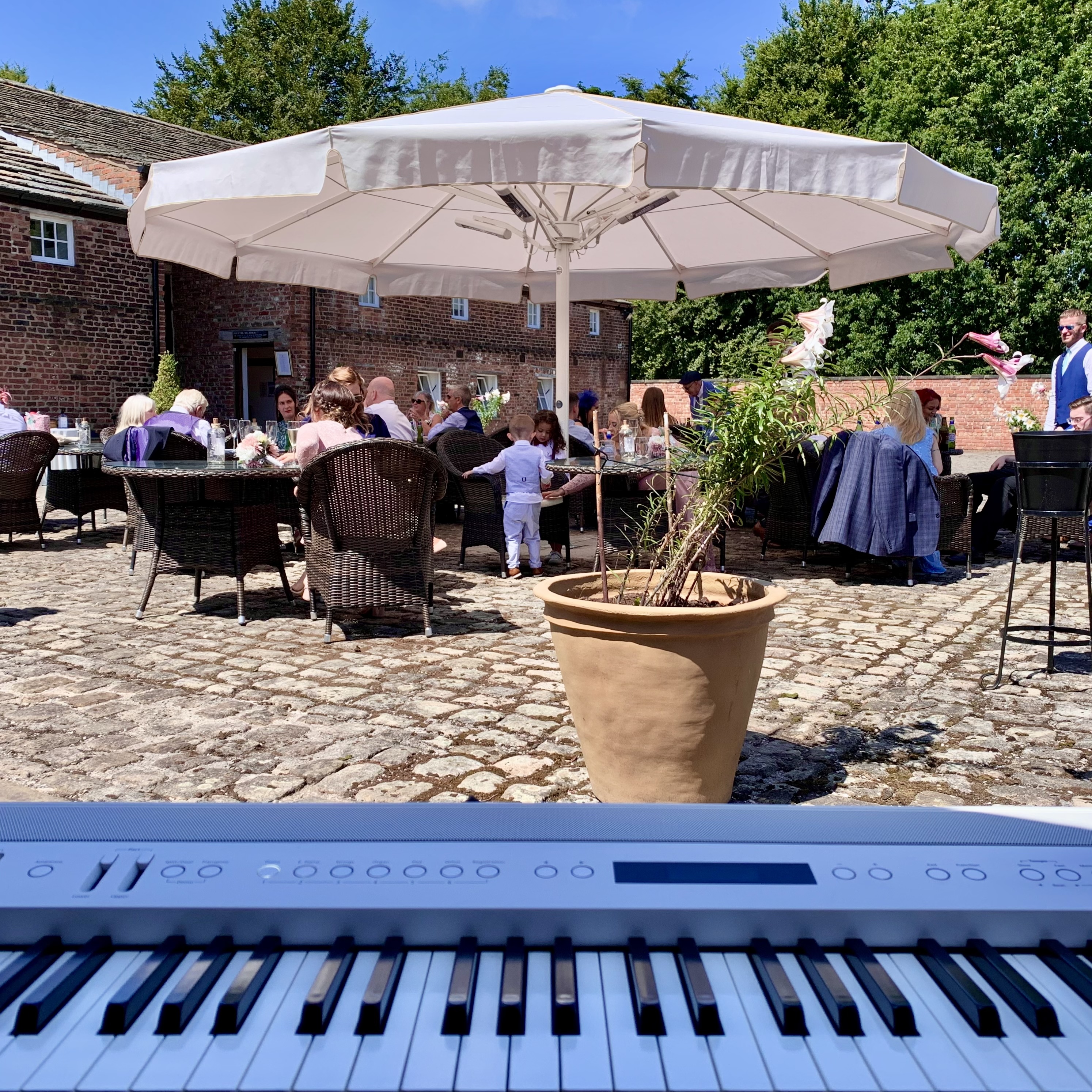 Live Meols Hall drinks reception music by wedding pianist Craig Smith, outside in the sunny courtyard