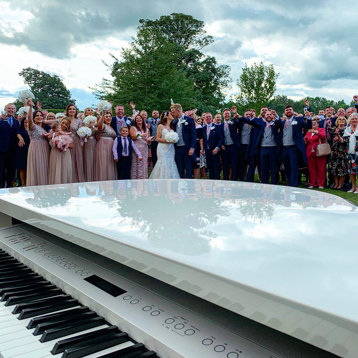 Wedding pianist Craig Smith plays his white piano in the garden as wedding guests cheer in the background
