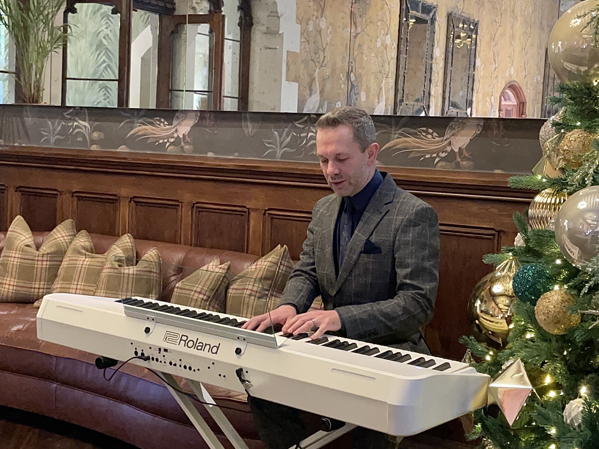 Wedding pianist Craig Smith chats while playing a white piano at Wennington Hall