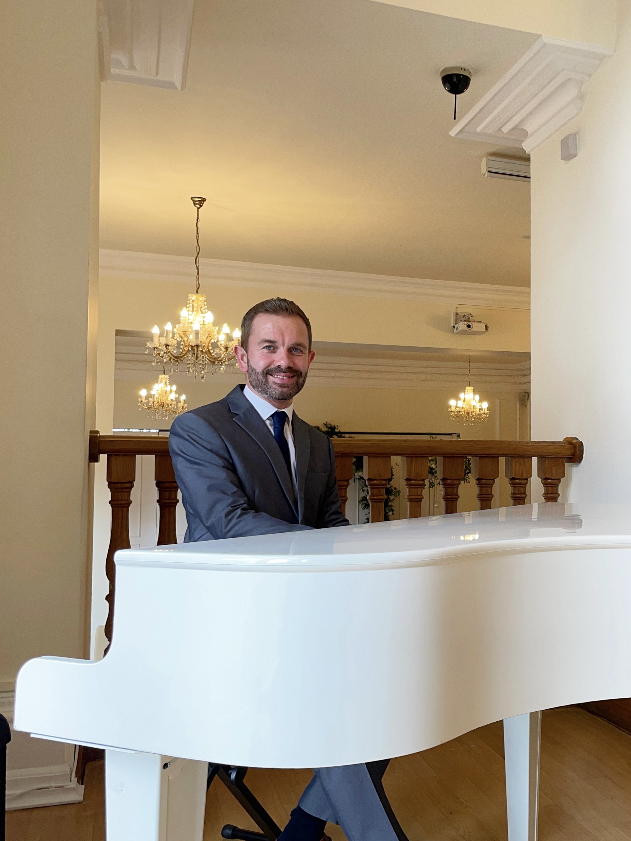 West Tower's recommended wedding pianist Craig Smith smiles from the piano ahead of a ceremony in The Ballroom.