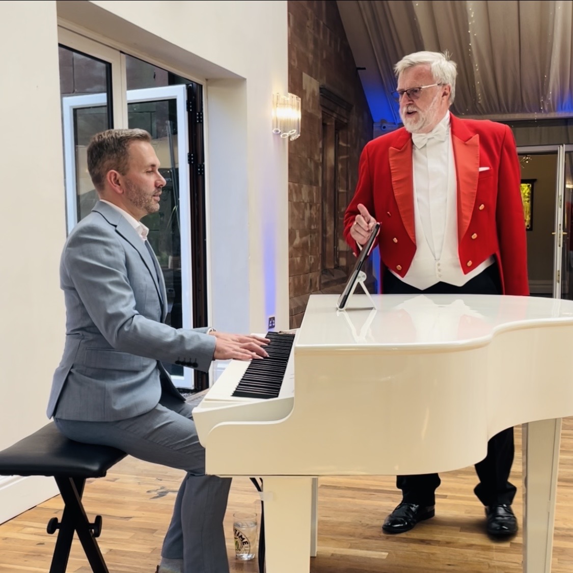 Wrenbury Hall wedding pianist Craig Smith chats with the toastmaster while playing for a wedding breakfast